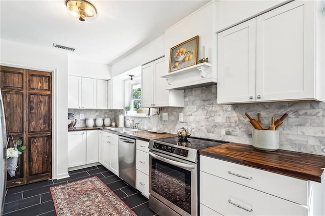 kitchen featuring visible vents, dark tile patterned floors, white cabinetry, wood counters, and stainless steel appliances