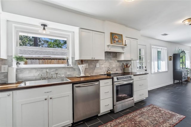 kitchen with butcher block countertops, visible vents, a sink, stainless steel appliances, and white cabinetry