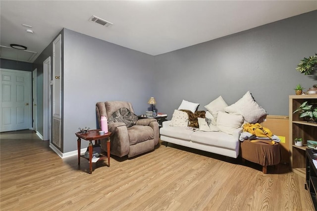 living area featuring baseboards, attic access, light wood finished floors, and visible vents