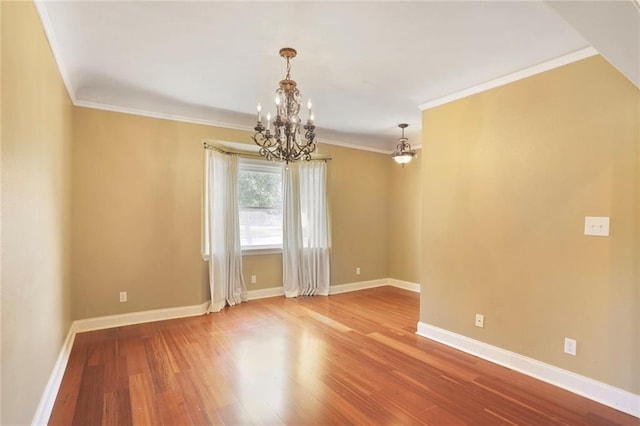 empty room featuring baseboards, ornamental molding, wood finished floors, and a chandelier