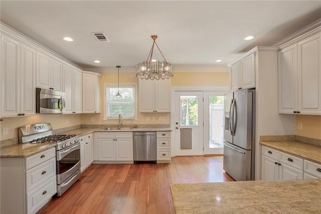 kitchen with appliances with stainless steel finishes, a sink, white cabinetry, light wood-type flooring, and visible vents