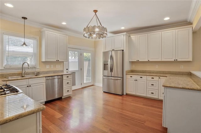 kitchen featuring a sink, white cabinetry, appliances with stainless steel finishes, and hanging light fixtures