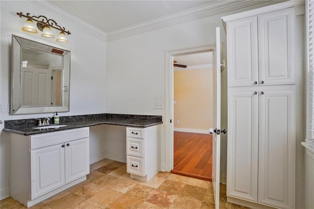 bathroom with vanity, ornamental molding, baseboards, and stone finish flooring