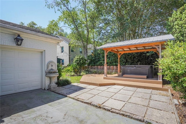view of patio featuring a gazebo, a garage, a hot tub, and driveway