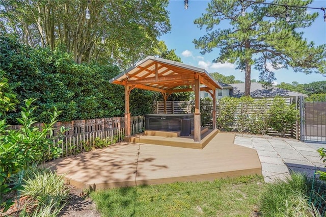 view of patio / terrace with fence, a covered hot tub, a wooden deck, and a gazebo