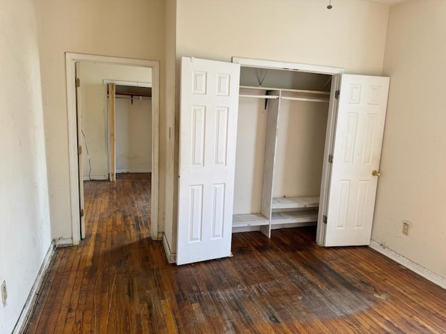 unfurnished bedroom featuring baseboards, dark wood finished floors, and a closet