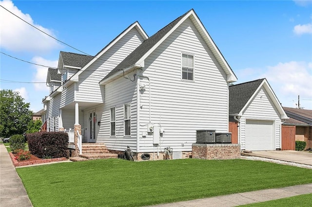 view of side of property with a lawn, driveway, roof with shingles, and a garage