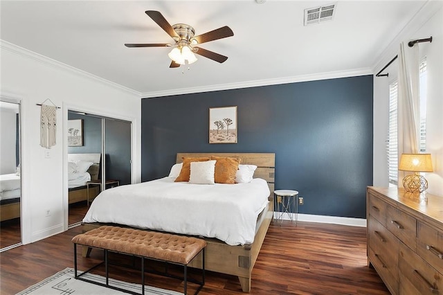 bedroom with crown molding, ceiling fan, baseboards, wood finished floors, and visible vents