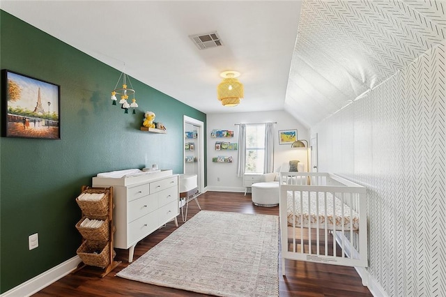 bedroom with a nursery area, baseboards, dark wood-style floors, and visible vents