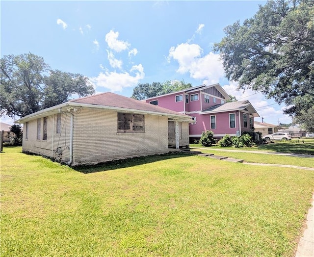 view of side of home featuring brick siding and a yard