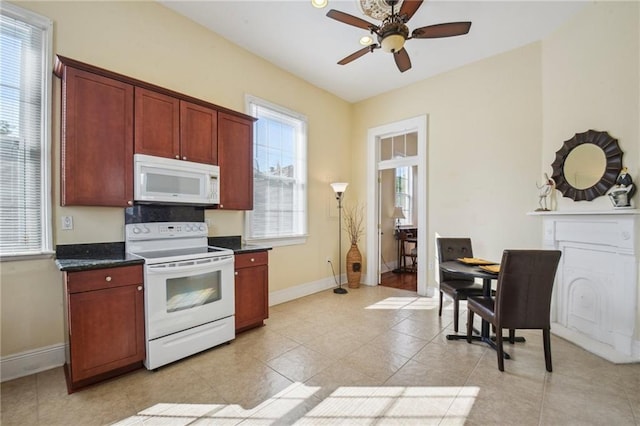 192426 Esplanade Ave, New Orleans, LA 70116 - kitchen with light tile patterned flooring, dark countertops, ceiling fan, white appliances, and baseboards