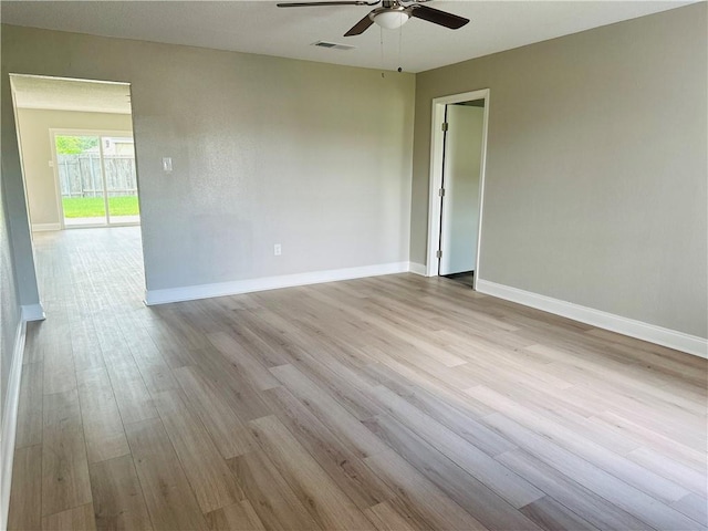 empty room with baseboards, ceiling fan, visible vents, and wood finished floors