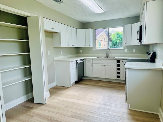 kitchen featuring a textured ceiling, appliances with stainless steel finishes, a sink, and light wood-type flooring