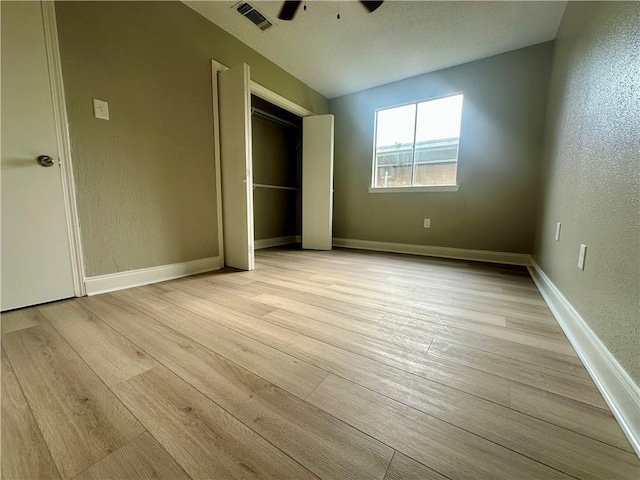 unfurnished bedroom with a textured wall, visible vents, and light wood-style flooring