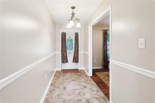 foyer with baseboards and a notable chandelier