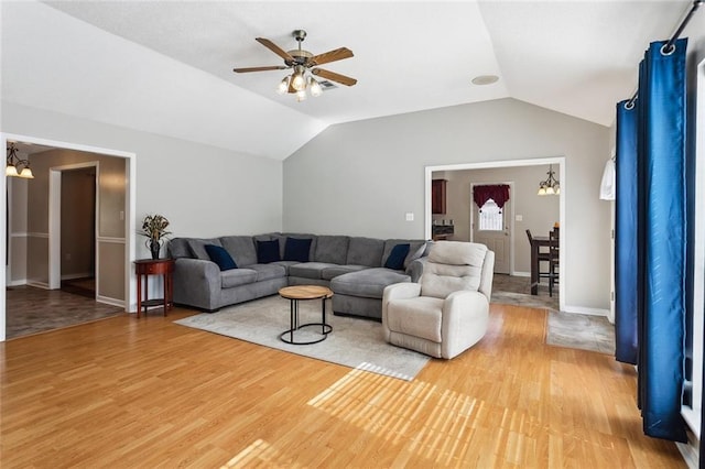 living room featuring a ceiling fan, baseboards, vaulted ceiling, and light wood-style floors
