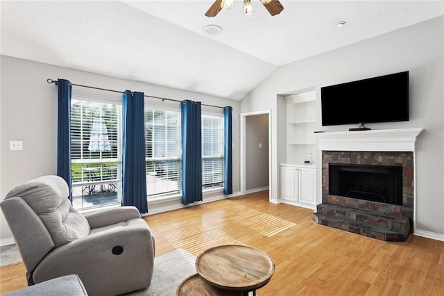 living room with ceiling fan, light wood-style floors, built in shelves, baseboards, and vaulted ceiling