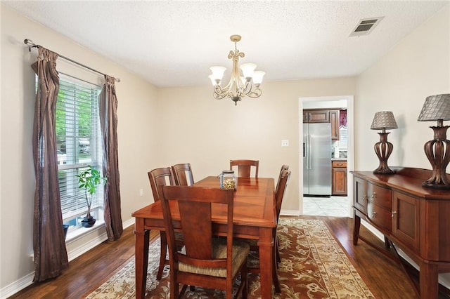 dining room with baseboards, a notable chandelier, wood finished floors, and visible vents