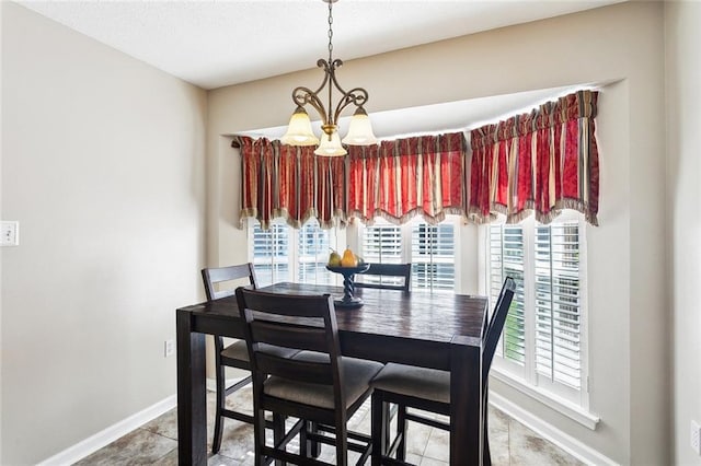 dining space featuring baseboards, tile patterned floors, and a chandelier