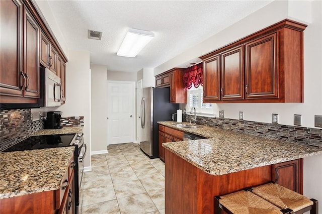 kitchen with a sink, stainless steel appliances, a peninsula, backsplash, and visible vents