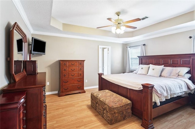 bedroom featuring visible vents, a raised ceiling, and light wood-style flooring