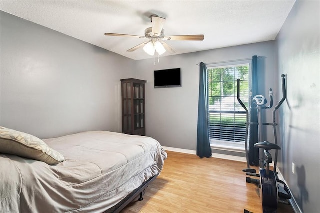 bedroom featuring a textured ceiling, baseboards, ceiling fan, and light wood finished floors