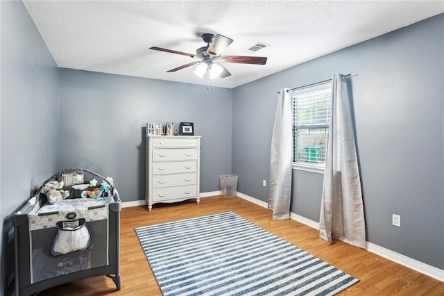 bedroom featuring a textured ceiling, ceiling fan, baseboards, and wood finished floors