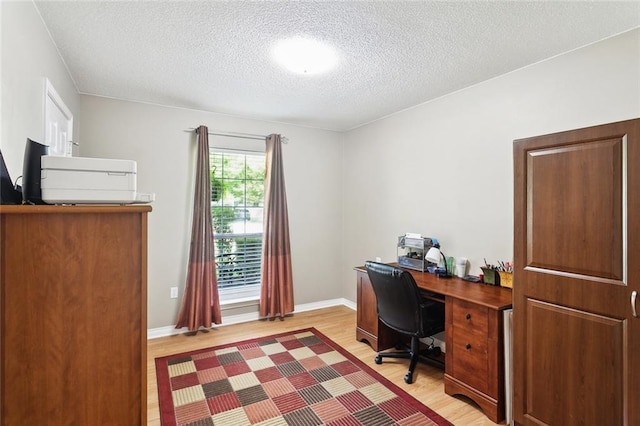 office space featuring a textured ceiling, baseboards, and light wood-type flooring