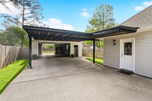 view of vehicle parking with concrete driveway, fence, and a carport