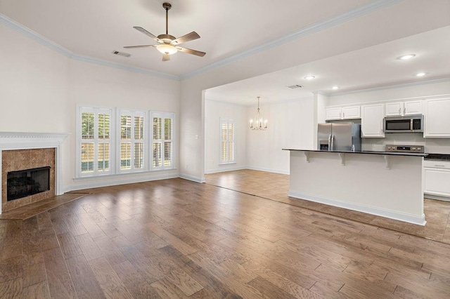 940 Woodsprings Ct, Covington, LA 70433 - unfurnished living room featuring wood finished floors, a fireplace, a chandelier, ornamental molding, and a ceiling fan