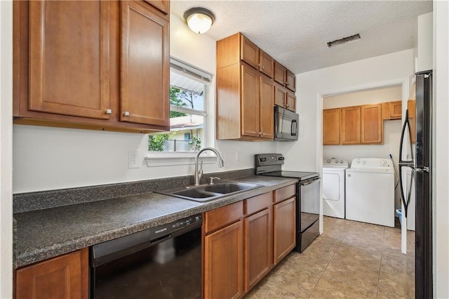 kitchen with dark countertops, brown cabinets, a sink, independent washer and dryer, and black appliances