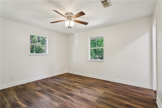 empty room featuring visible vents, dark wood-style flooring, ceiling fan, and baseboards