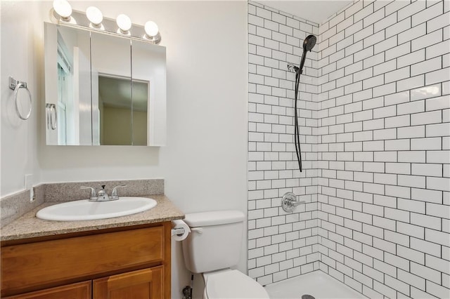 full bathroom featuring vanity, toilet, and tiled shower