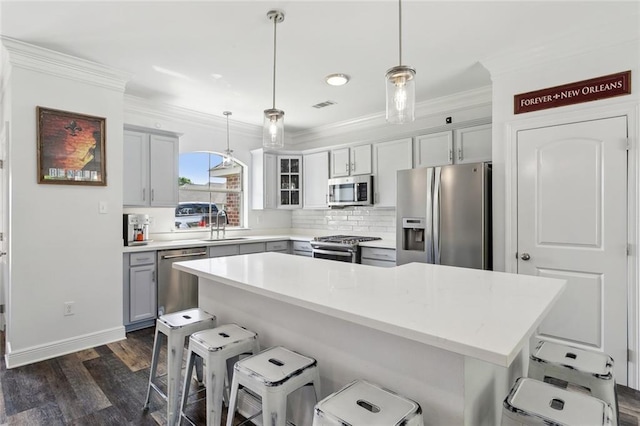 kitchen with crown molding, appliances with stainless steel finishes, a kitchen bar, and visible vents