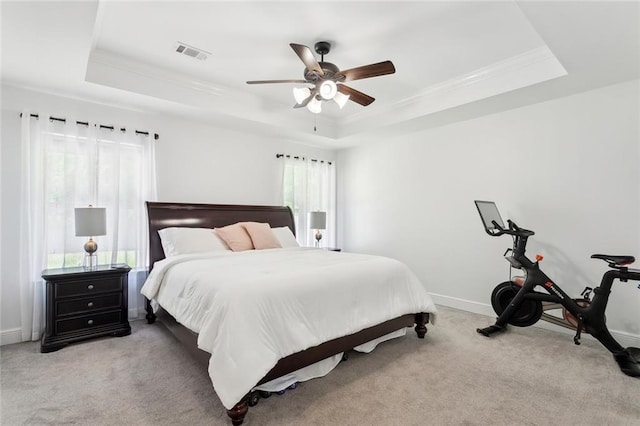 bedroom featuring crown molding, light colored carpet, a tray ceiling, and visible vents