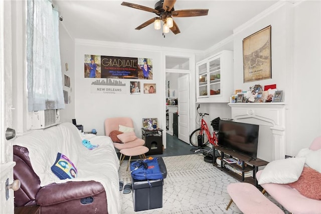 living area featuring crown molding, a ceiling fan, wood finished floors, and a fireplace