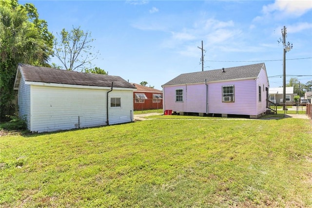 rear view of property with fence, an outdoor structure, and a yard
