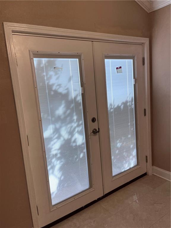 entryway featuring light tile patterned floors, baseboards, ornamental molding, and french doors