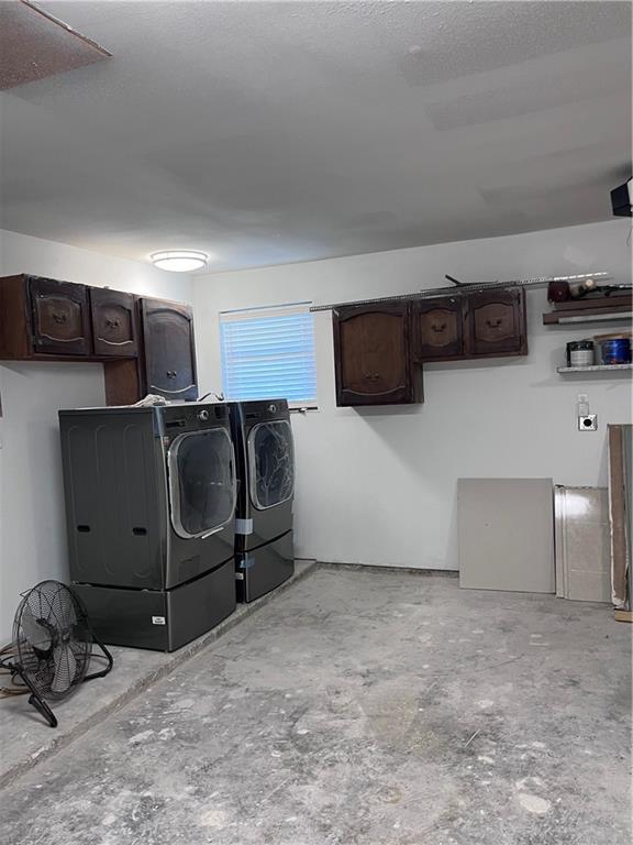 laundry area featuring separate washer and dryer, a textured ceiling, and cabinet space