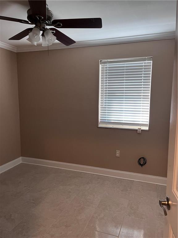 empty room featuring baseboards, ornamental molding, and ceiling fan