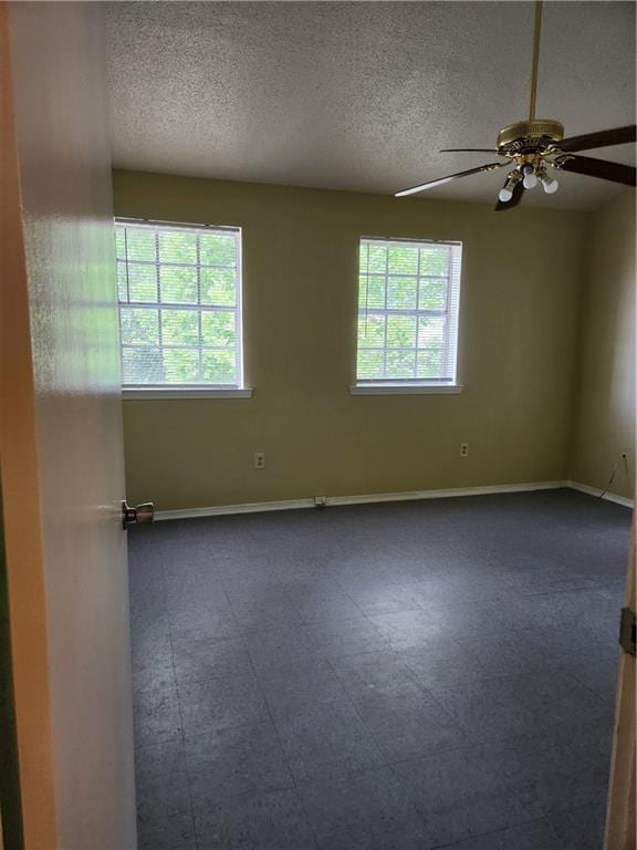 empty room featuring baseboards, a ceiling fan, and a textured ceiling