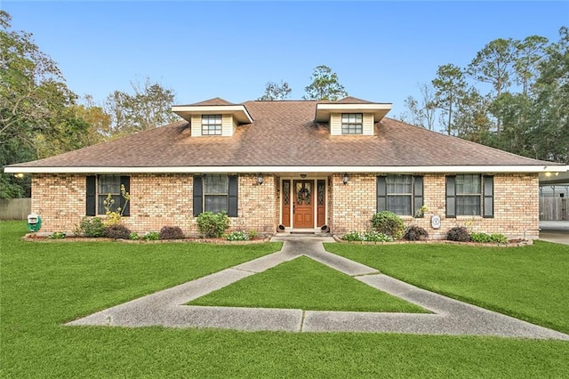 view of front facade with roof with shingles, a front yard, and brick siding