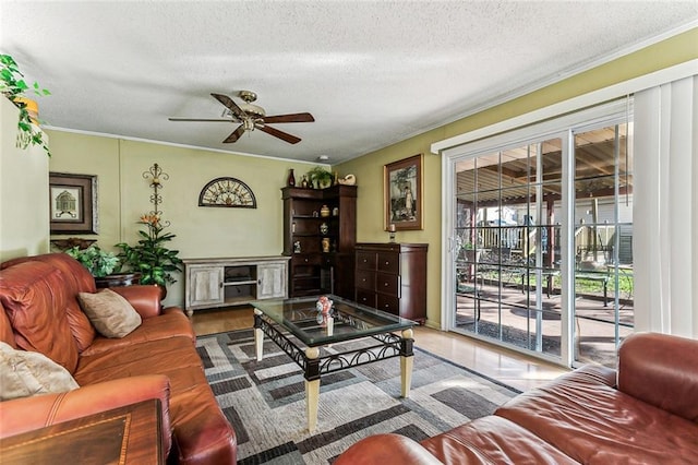 living room with a ceiling fan, a textured ceiling, and ornamental molding