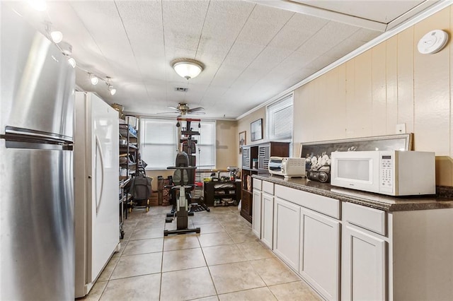 kitchen with crown molding, dark countertops, white microwave, a ceiling fan, and light tile patterned floors