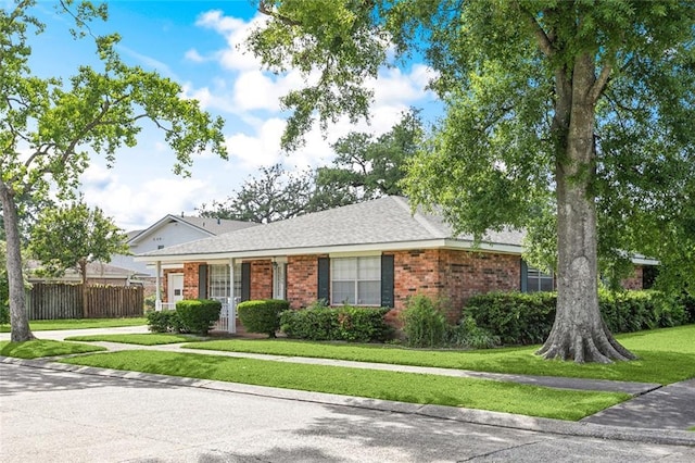 ranch-style house with brick siding, a front lawn, and fence