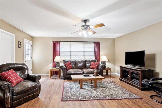 living area with baseboards, ceiling fan, and wood finished floors