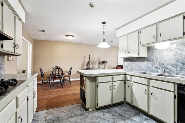 kitchen with a sink, light countertops, a peninsula, backsplash, and visible vents