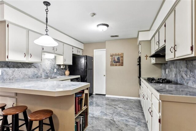 kitchen featuring black appliances, decorative backsplash, under cabinet range hood, and visible vents