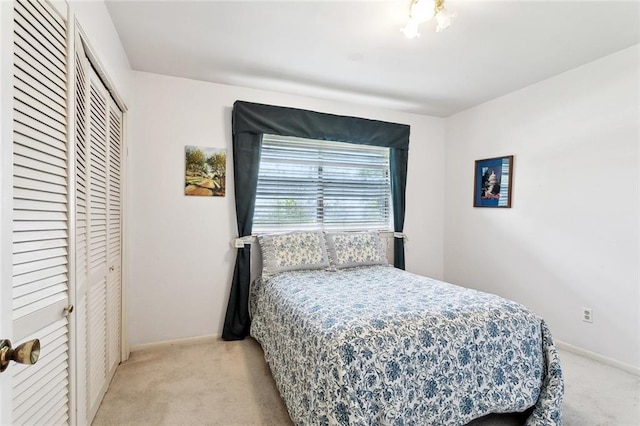 bedroom with baseboards, light carpet, and a closet