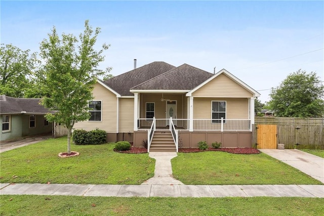 view of front of home with a shingled roof, a front lawn, fence, and covered porch